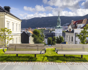 Zwei Bänke neben dem Bürgersteig und Blick auf die Nykirken-Kirche in Bergen, Norwegen