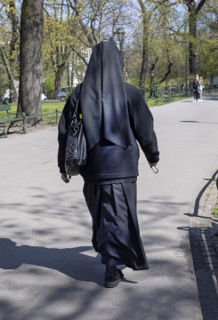 Eine Nonne geht den Bürgersteig entlang