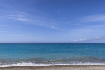 Meer, steiniger Strand und ebener Horizont stockfoto