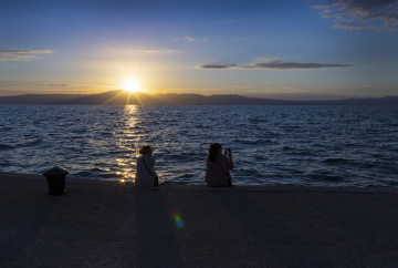 Sonnenuntergang am Meer und Personen am Ufer