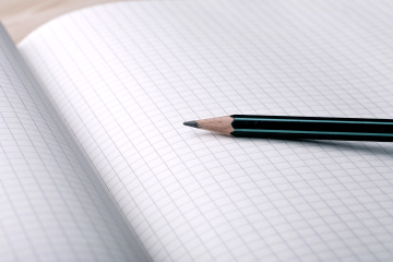 Kariertes Notizbuch und grüner Bleistift
