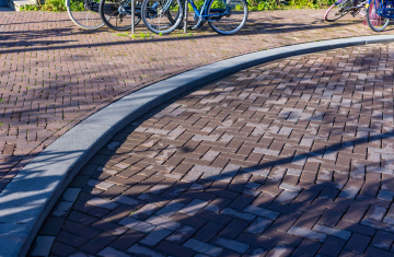 Eine Kurve und Fahrräder, die am Bordstein aus Granit geparkt sind