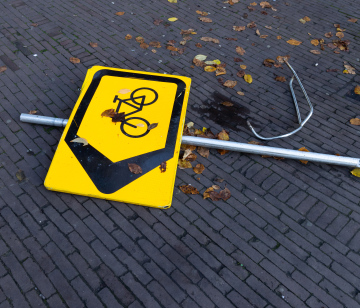 Umgestürztes Straßenschild, Richtung für Fahrräder.