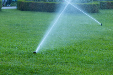 Bewässerung im Stadtpark. Sprinkler auf dem Rasen.
