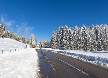 Winterlandschaft und schmelzender Schnee auf der Straße