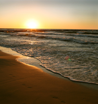 Sonnenuntergang über dem Meer und Schritte auf dem Sand