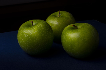 Drei grüne Äpfel auf einem dunklen Hintergrund