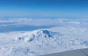 Blick auf die schneebedeckten Berge aus dem Flugzeugfenster