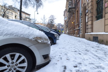 Auf der Straße geparkte Autos und Schnee auf dem Bürgersteig.