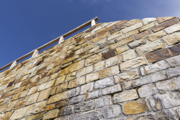 Hohe Steinmauer mit Holzgeländer