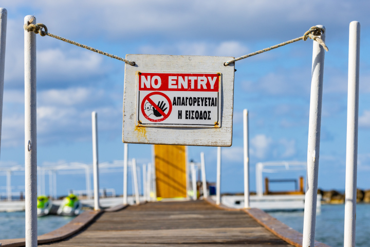 Geschlossener Eingang zum Pier, geschlossener Strand, Inschrift in Englisch und Griechisch, Stock Foto