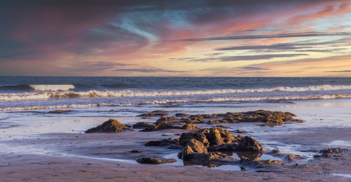 Vulkangestein am Strand und der Abendhimmel über dem Horizont