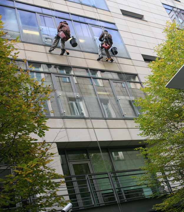 Fensterreinigung in einem Bürogebäude an Seilen